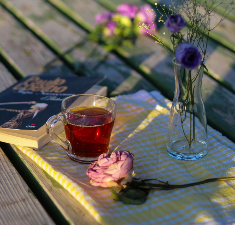 Teeglas mit Blumenstrauß und Buch zum Genießen