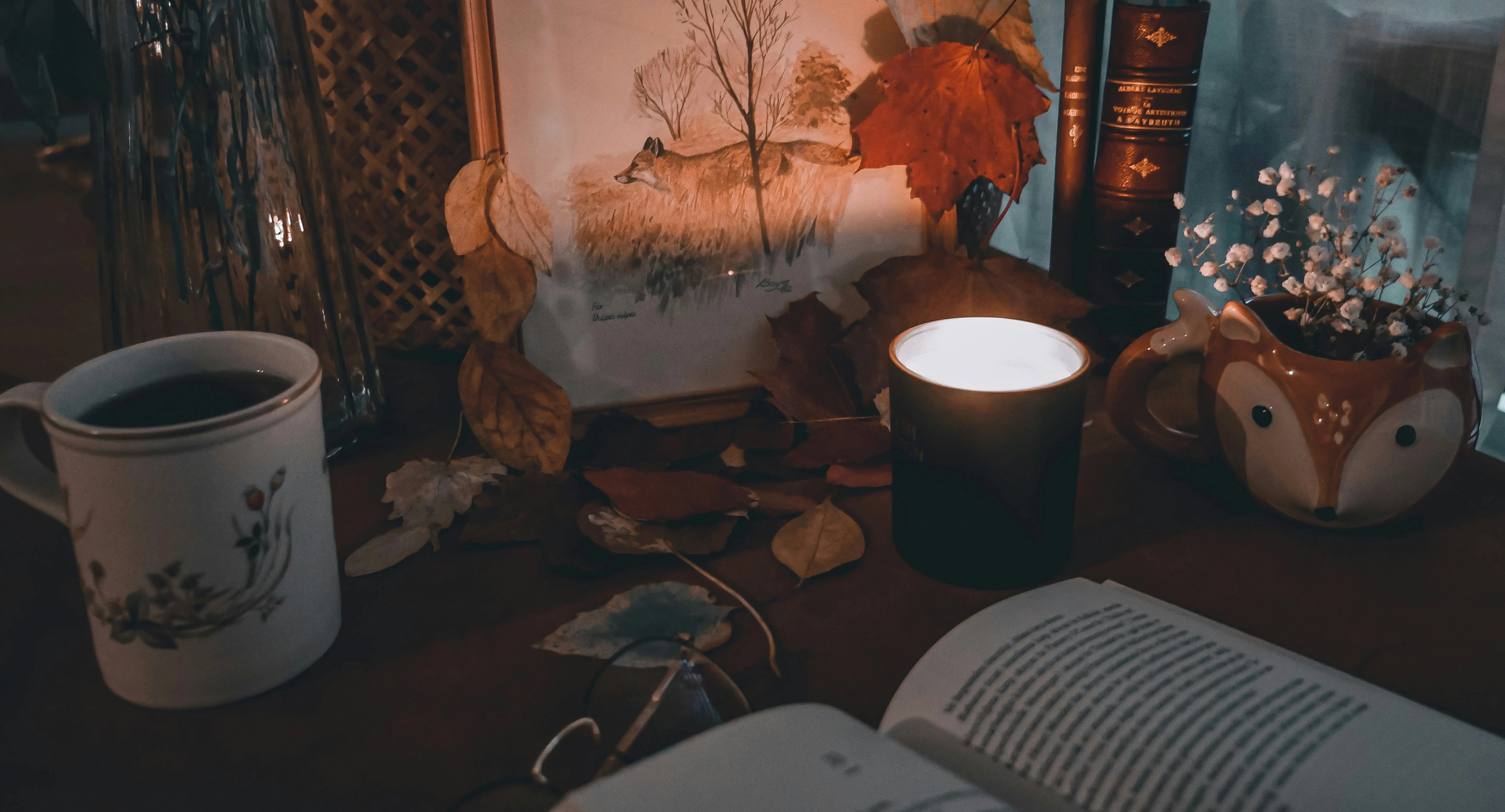 Gemütliche Szene mit Tee, Kerzenschein und einem Buch zum entspannen in der Herbstzeit