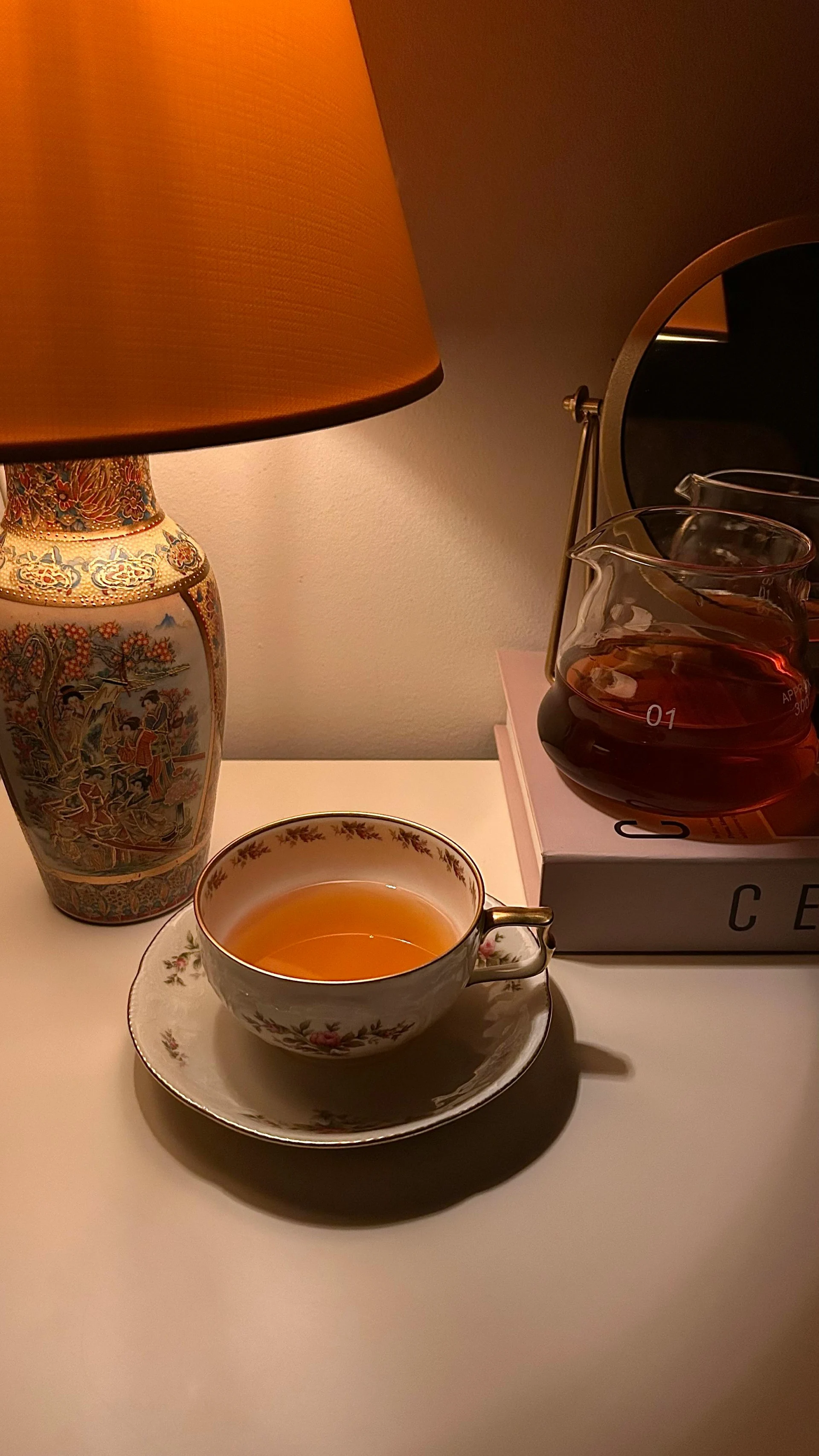 Tasse Tee bei Lampenschein am Abend neben einem Buch