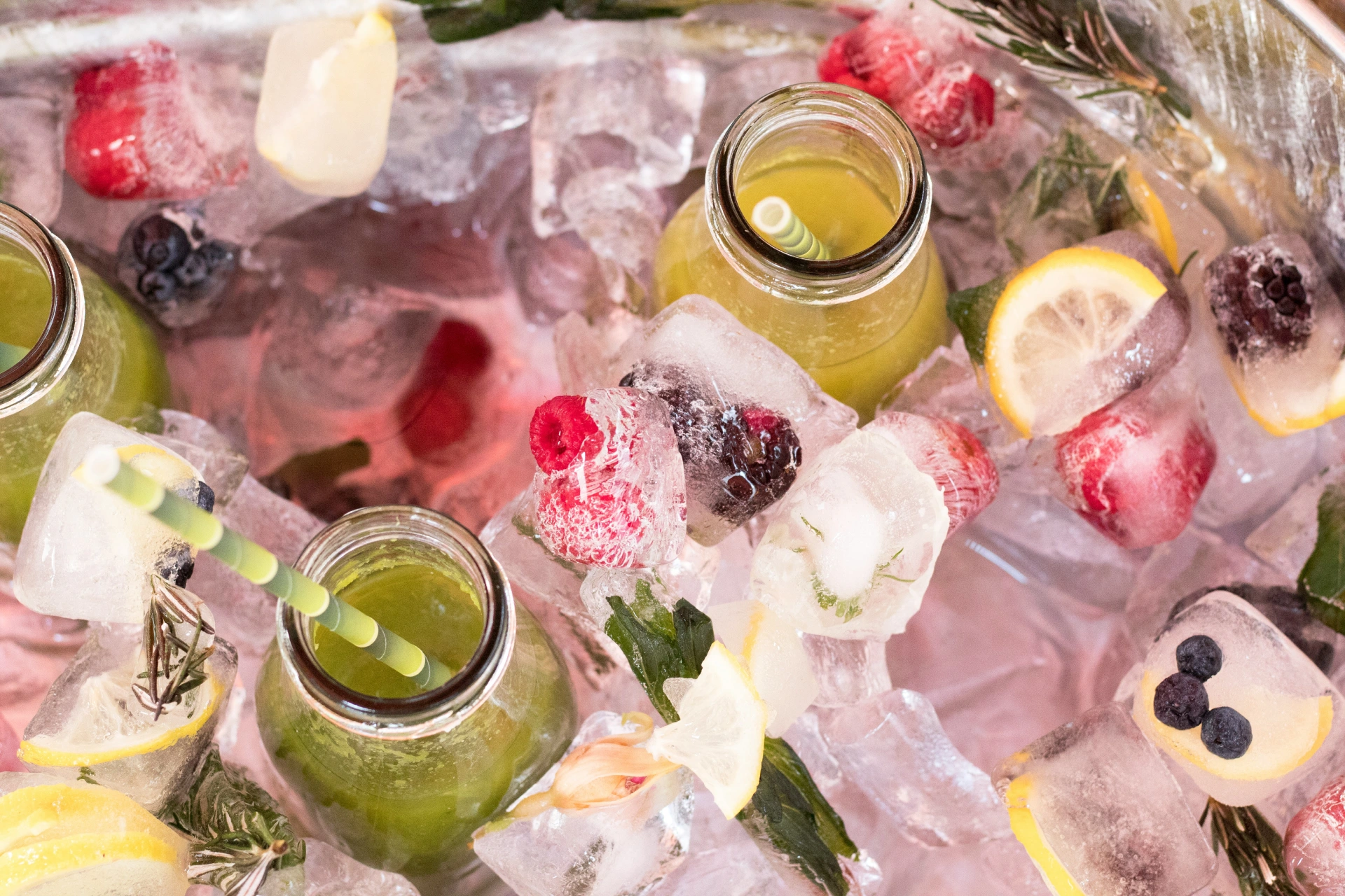 Eistee in Gläsern zwischen gefrorenen Eiswürfeln mit Obst und Beeren
